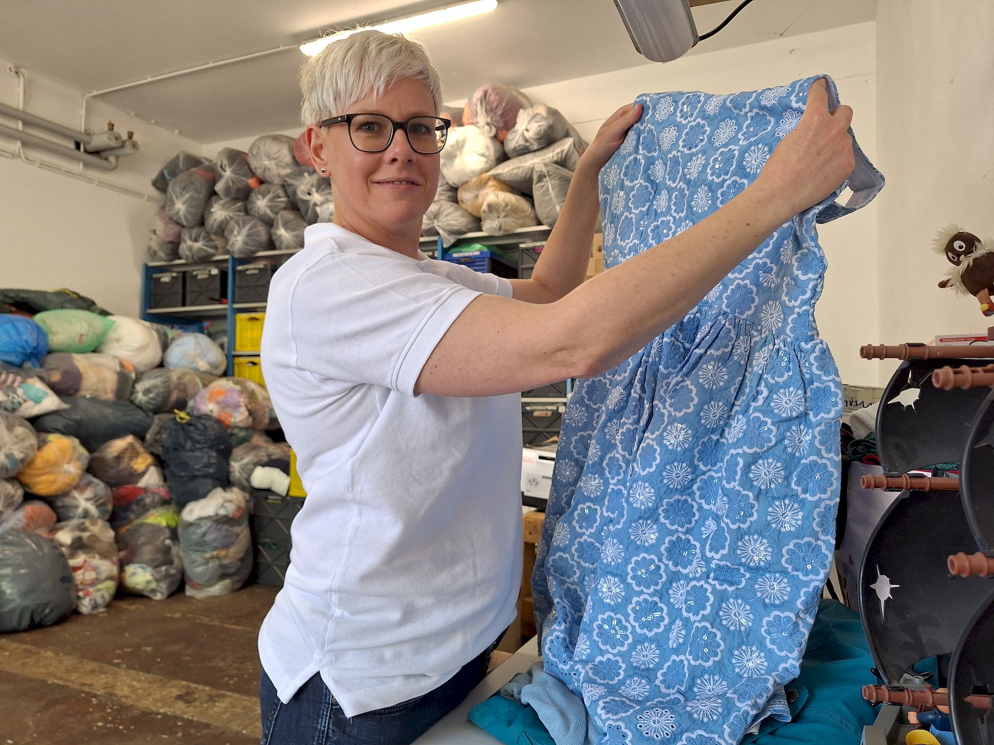 Ulrike Peter, Sprecherin des DRK in Dresden, zeigt eines der gelieferten Kleidungsstücke im Pieschener Lager.