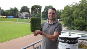 Abteilungsleiter Sportstätten Nico Seidel präsentiert den neuen Kunstrasen. Damit soll der Hartplatz künftig ganzjährig bespielbar werden. Foto: J. Frintert
